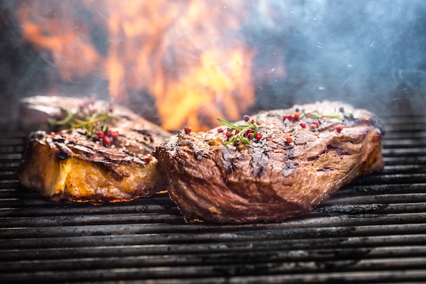Two steaks cooking on a grill.
