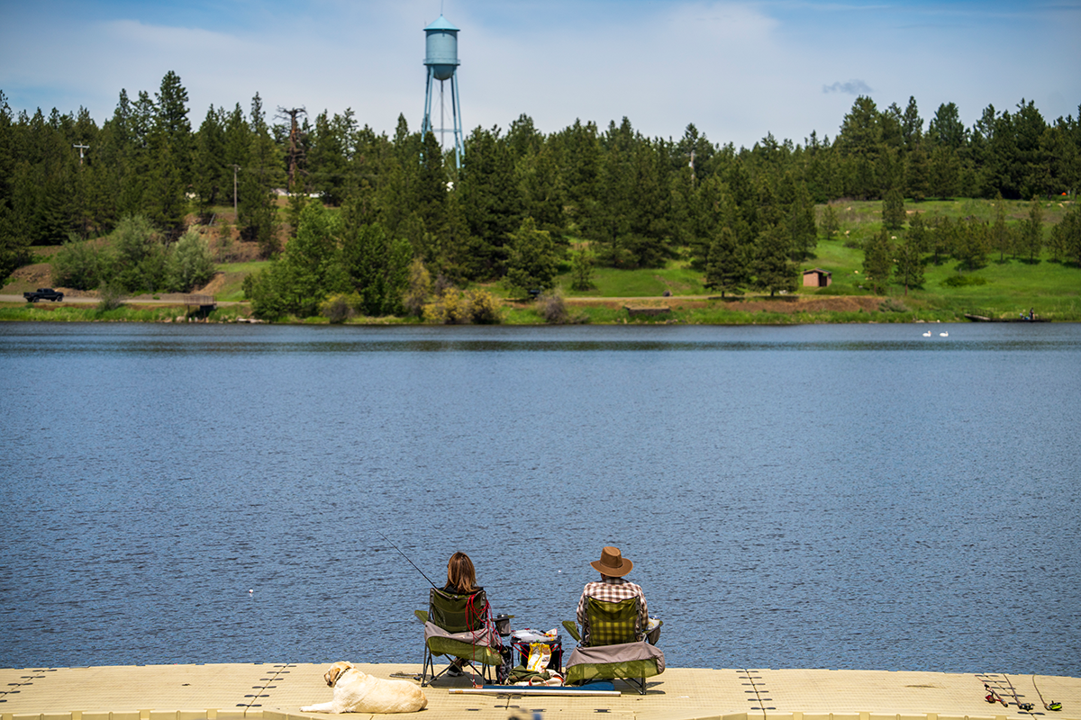 Man and woman sitting in front of lake fishing.