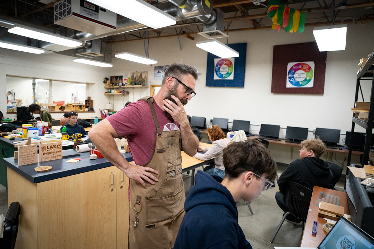 Man inspecting computer over student's shoulder